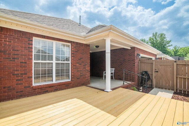wooden terrace with a gate, fence, and a patio