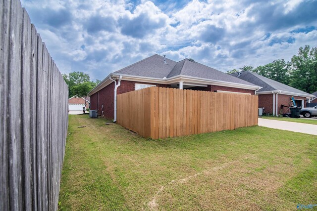 view of side of home featuring brick siding, central AC, driveway, and roof with shingles