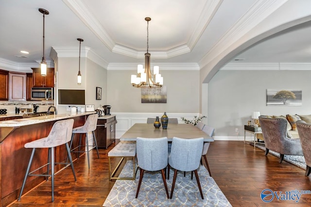 dining area featuring arched walkways, crown molding, dark wood-type flooring, and a tray ceiling