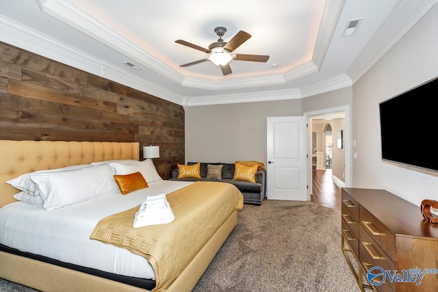 carpeted bedroom with a tray ceiling, arched walkways, visible vents, and ornamental molding