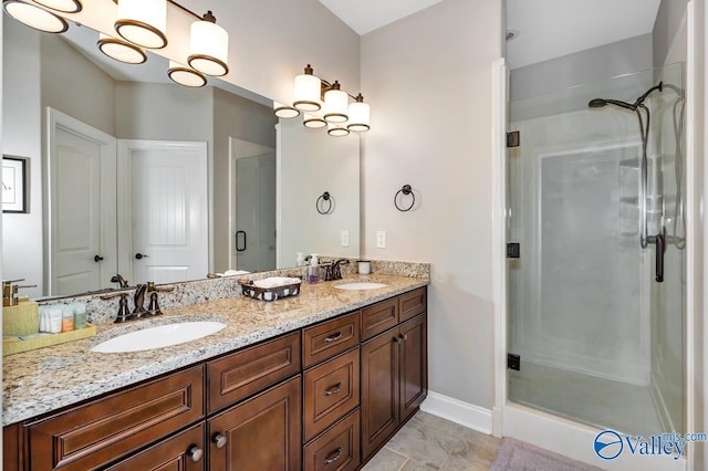 bathroom with double vanity, a stall shower, baseboards, and a sink