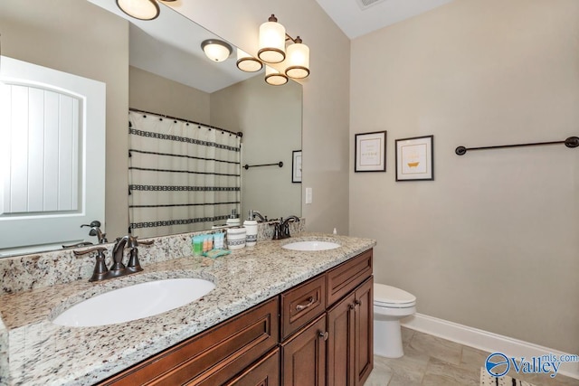 bathroom featuring double vanity, toilet, baseboards, and a sink