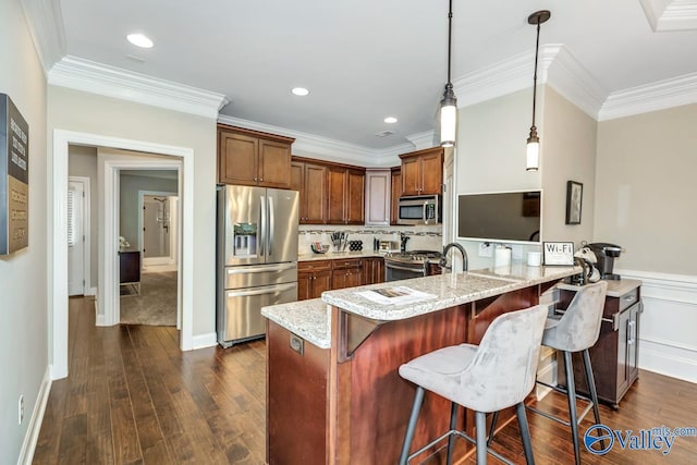 kitchen with light stone countertops, a breakfast bar, a peninsula, stainless steel appliances, and decorative light fixtures