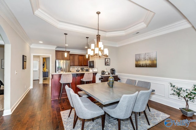 dining space with visible vents, a raised ceiling, dark wood finished floors, and crown molding