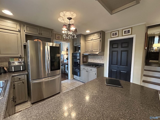 kitchen featuring appliances with stainless steel finishes, hanging light fixtures, light tile patterned flooring, decorative backsplash, and a chandelier