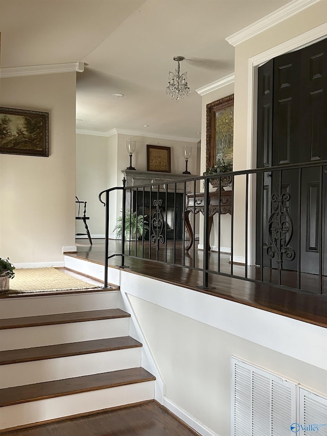 staircase with crown molding, hardwood / wood-style floors, and a notable chandelier