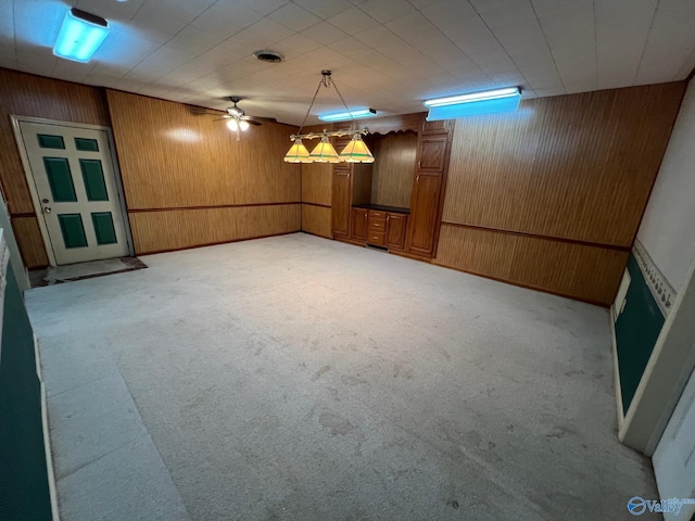 basement featuring light colored carpet and wooden walls