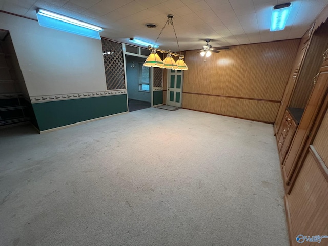 basement featuring light carpet and wooden walls