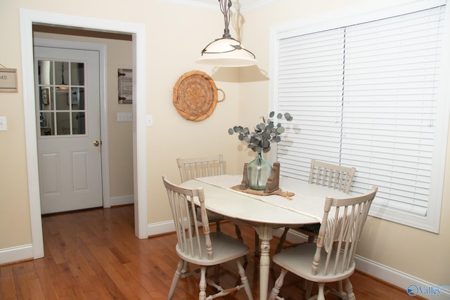 dining room with crown molding, baseboards, and light wood finished floors