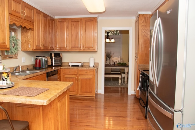 kitchen with a sink, light countertops, appliances with stainless steel finishes, and light wood-style floors
