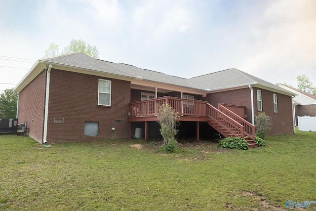 rear view of house with brick siding, stairway, a wooden deck, and a lawn