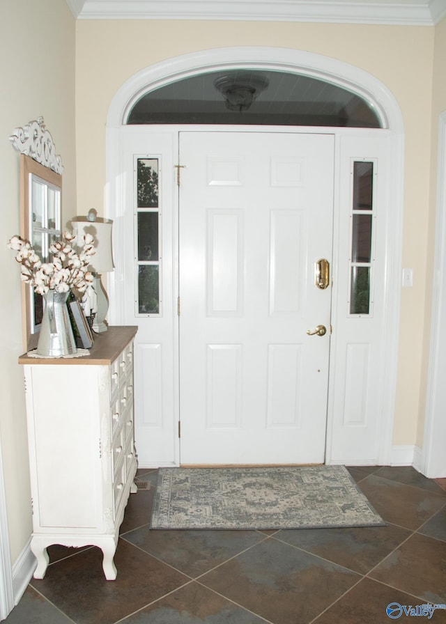 entrance foyer featuring baseboards, ornamental molding, and dark tile patterned flooring