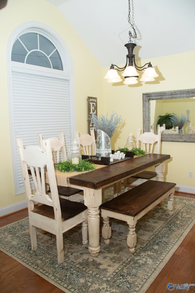 dining area with a chandelier, vaulted ceiling, and wood finished floors