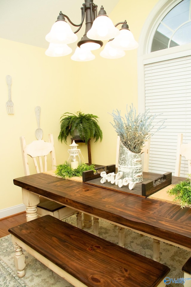 dining space featuring a notable chandelier, baseboards, and wood finished floors