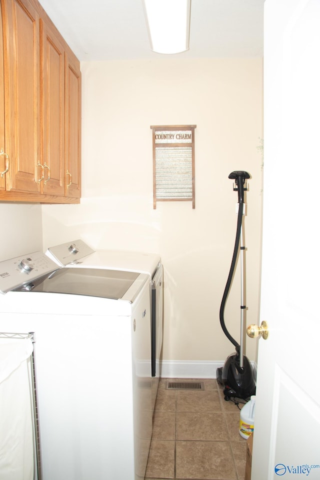 laundry area with light tile patterned floors, visible vents, washing machine and dryer, baseboards, and cabinet space