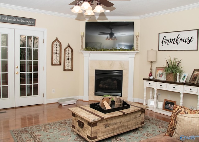 living area with crown molding, french doors, wood finished floors, and a premium fireplace