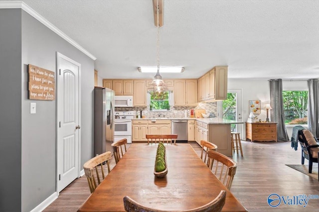 dining space with ornamental molding, a wealth of natural light, a textured ceiling, and light wood-style flooring