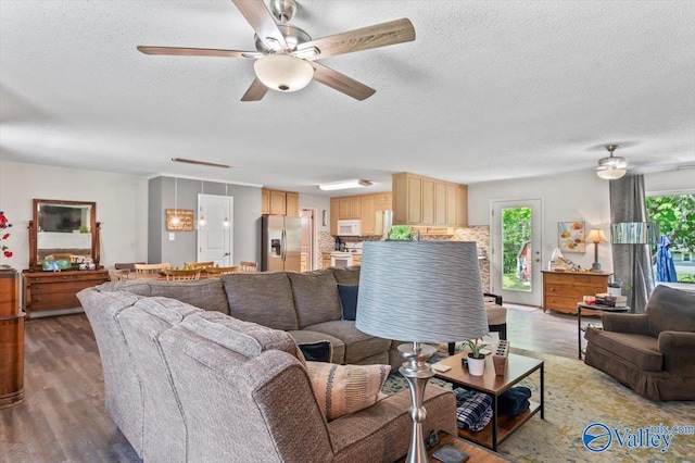 living room featuring light wood-style floors, ceiling fan, and a textured ceiling