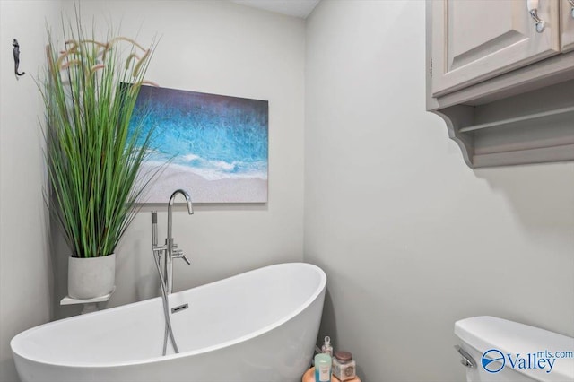 full bathroom with toilet, a soaking tub, and a sink
