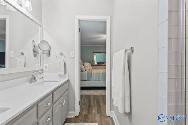 ensuite bathroom with wood finished floors, double vanity, ornamental molding, ensuite bathroom, and a sink