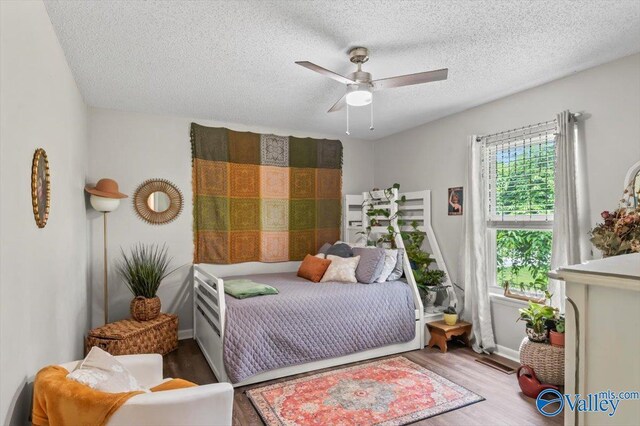 bedroom with wood finished floors, ceiling fan, baseboards, visible vents, and a textured ceiling