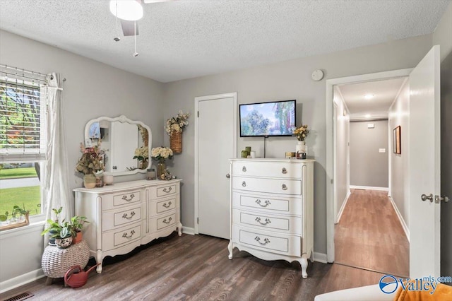 bedroom featuring ceiling fan, visible vents, baseboards, a textured ceiling, and dark wood finished floors