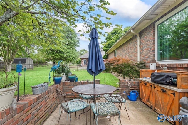 view of patio featuring an outdoor structure, outdoor dining area, and fence