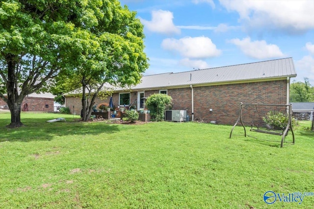 back of house featuring metal roof, a lawn, and brick siding