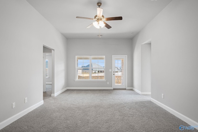 carpeted empty room with a ceiling fan and baseboards