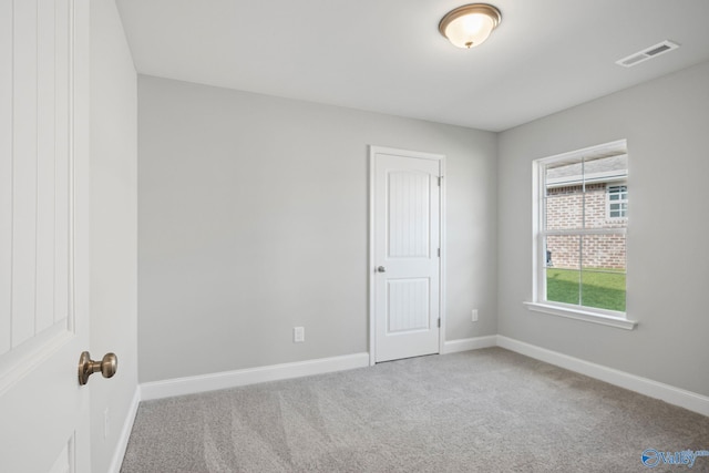 spare room with carpet, visible vents, and baseboards