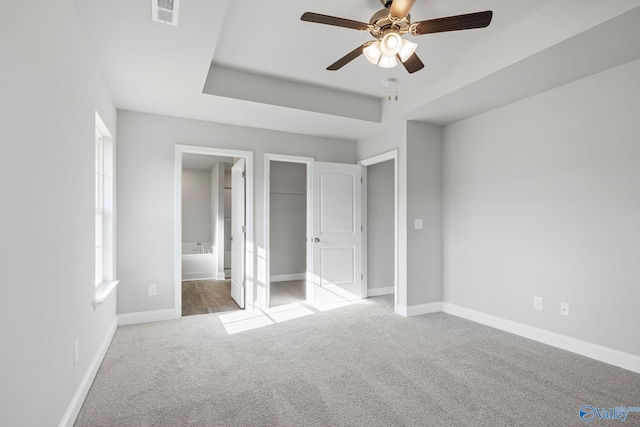 unfurnished bedroom featuring carpet, a raised ceiling, visible vents, and baseboards