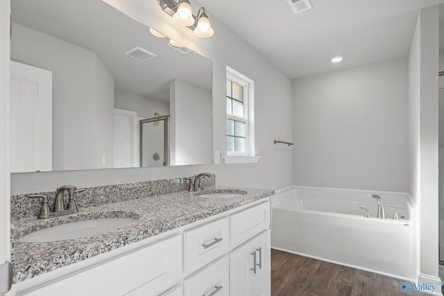 bathroom with double vanity, wood finished floors, a sink, and visible vents