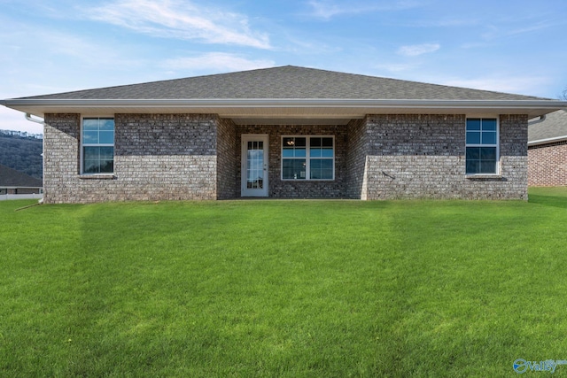 ranch-style home featuring a shingled roof, a front yard, and brick siding