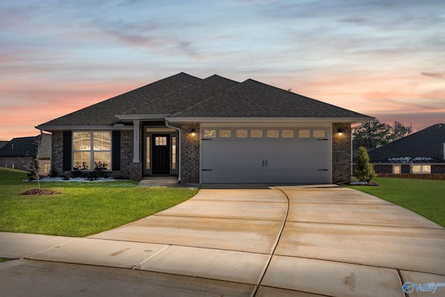 view of front of home featuring driveway, an attached garage, a shingled roof, and a front yard