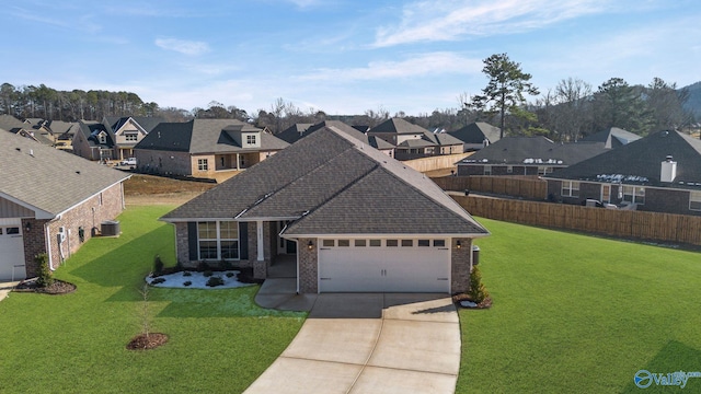 view of front of property featuring a residential view, driveway, an attached garage, and a front yard