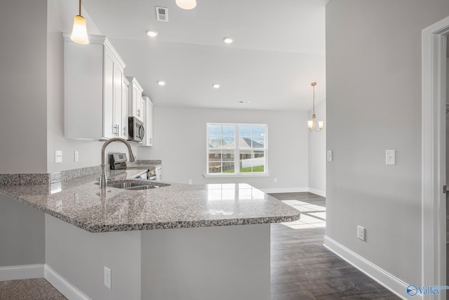 kitchen featuring light stone counters, visible vents, appliances with stainless steel finishes, white cabinets, and a sink