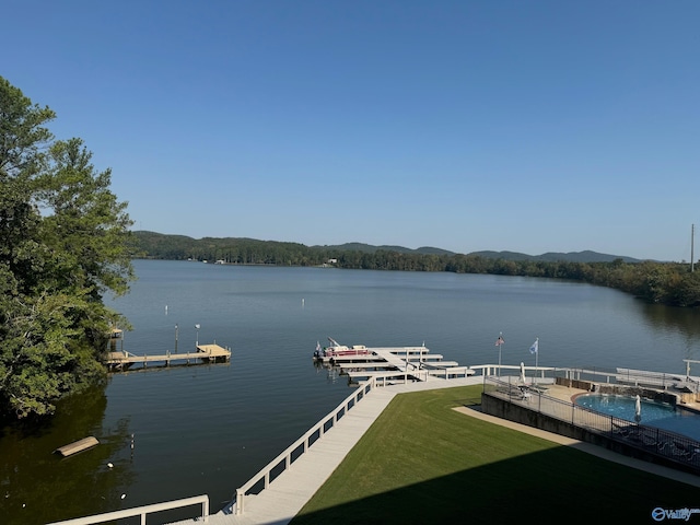 view of dock with a water view, a fenced in pool, and a yard