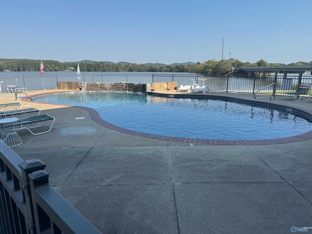 view of pool with a water view and a patio area