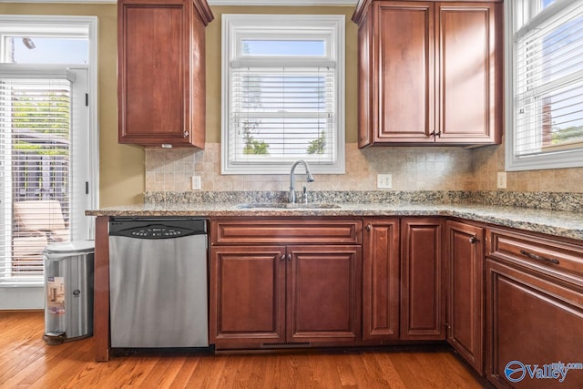 kitchen with wood finished floors, a sink, backsplash, and dishwasher
