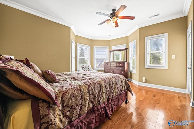 bedroom featuring ceiling fan, visible vents, baseboards, ornamental molding, and light wood-style flooring