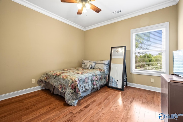 bedroom featuring a ceiling fan, visible vents, crown molding, baseboards, and light wood-style flooring
