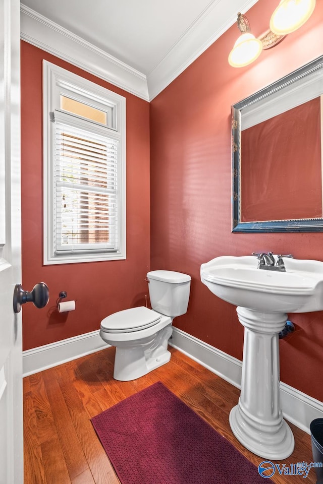 half bath with crown molding, toilet, baseboards, and wood finished floors