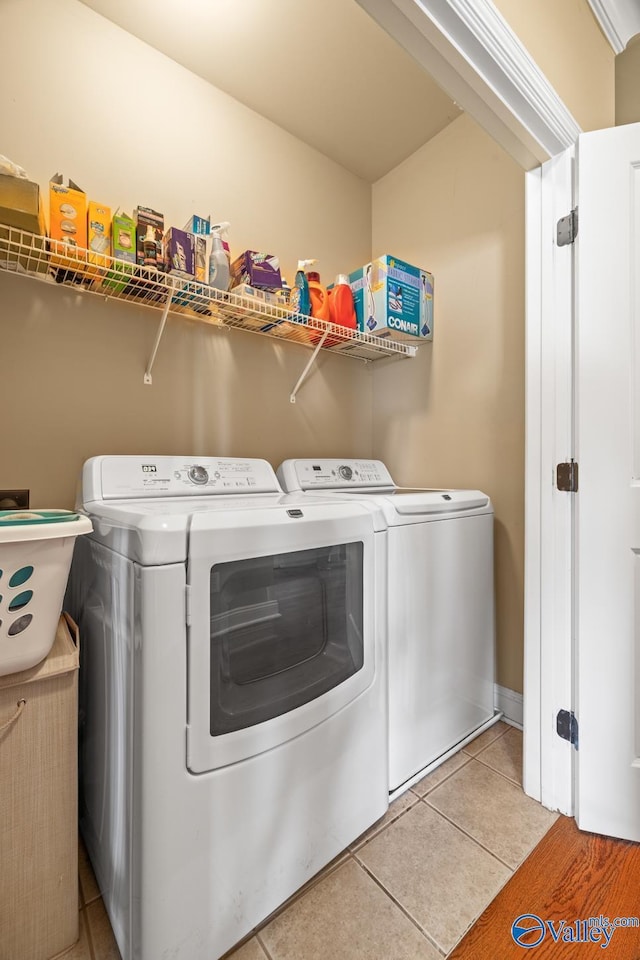 laundry room with laundry area, independent washer and dryer, and light tile patterned floors
