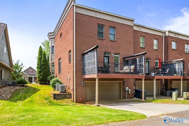 rear view of property featuring a lawn, an attached garage, cooling unit, and brick siding