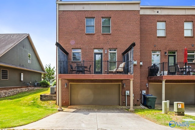 view of front facade with concrete driveway, brick siding, an attached garage, and central AC unit