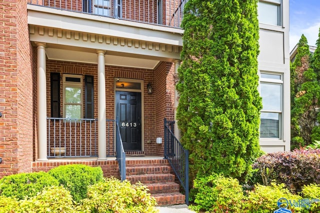 entrance to property featuring brick siding and covered porch