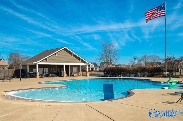 community pool with a patio area and fence