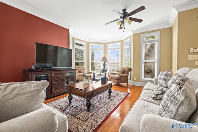 living area with baseboards, ornamental molding, a ceiling fan, and wood finished floors
