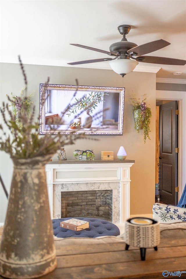 living area with crown molding, ceiling fan, and a fireplace