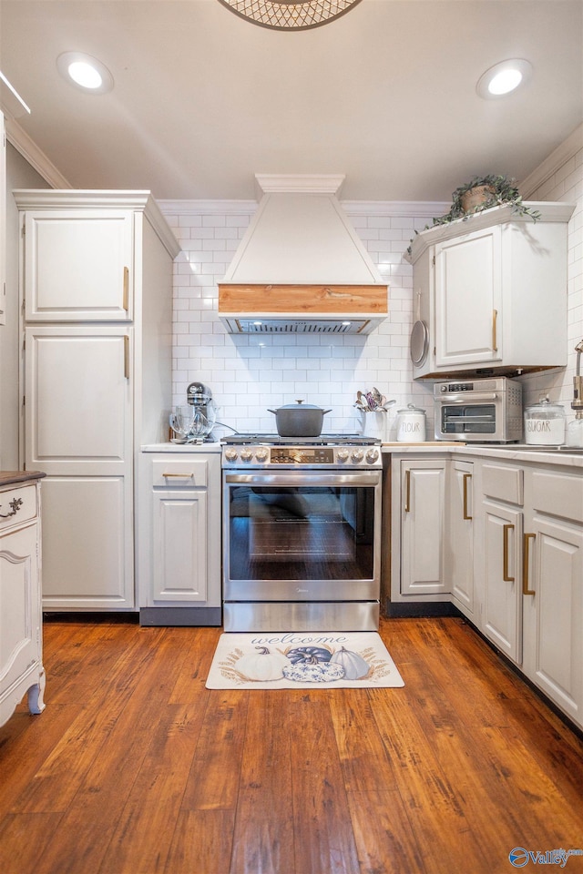 kitchen featuring gas range, white cabinetry, crown molding, and custom range hood